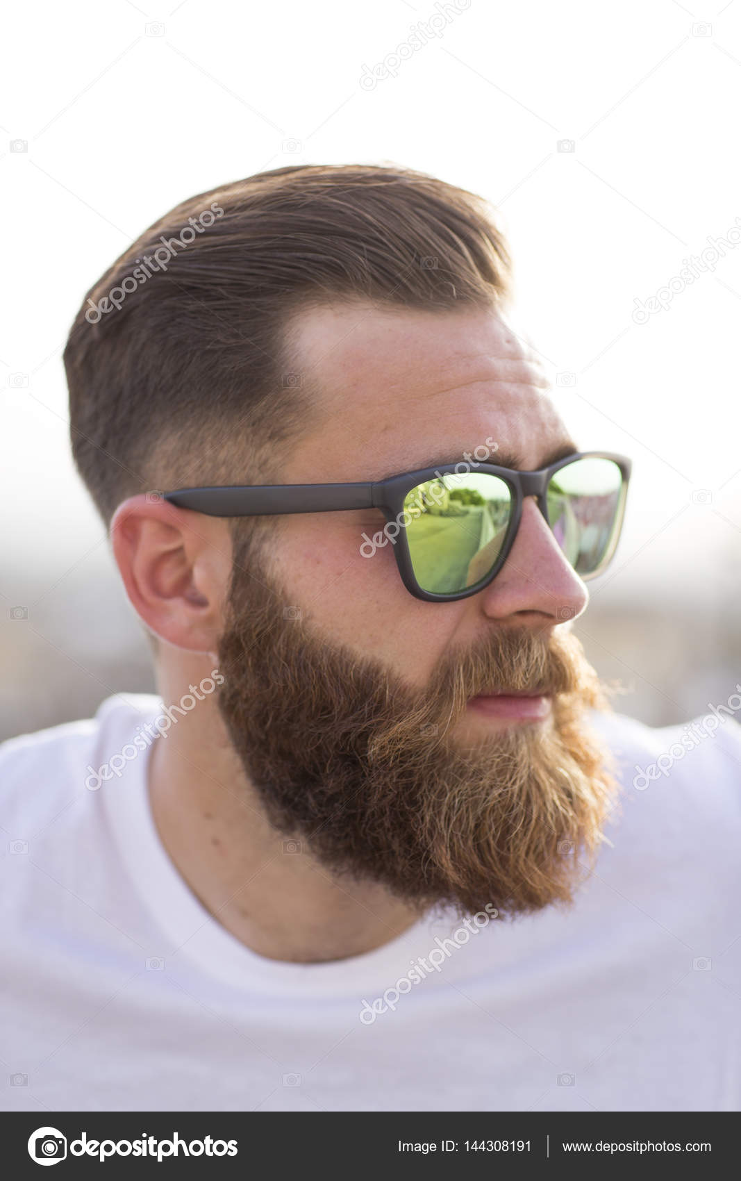 Бородатый мужчина позирует на улице в солнечных очках . стоковое фото ©juananbarros 144308191