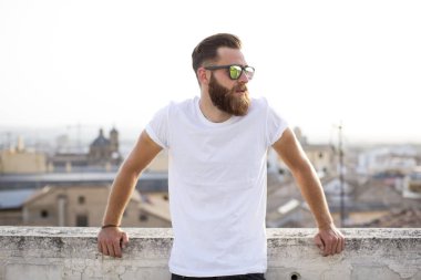 Sakallı adam sokakta güneş gözlüğü ile poz.