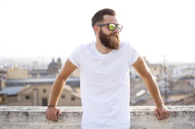 Sakallı adam sokakta güneş gözlüğü ile poz.