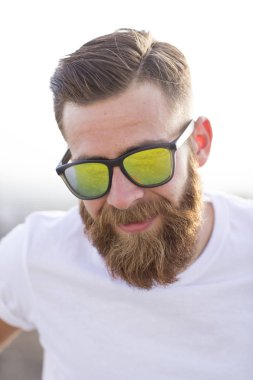 Sakallı adam sokakta güneş gözlüğü ile poz.