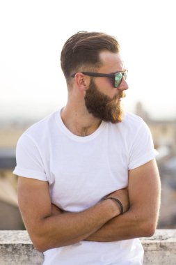 Sakallı adam sokakta güneş gözlüğü ile poz.