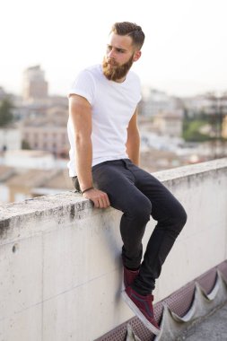 Sakallı adam sokakta poz.