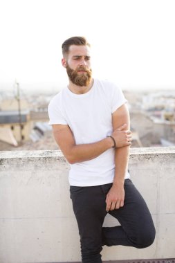 Sakallı adam sokakta poz.