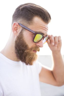 Sakallı adam sokakta güneş gözlüğü ile poz.