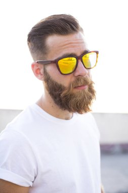 Sakallı adam sokakta güneş gözlüğü ile poz.