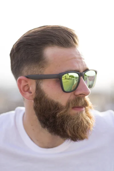 Бородатый мужчина позирует на улице в солнечных очках . — стоковое фото