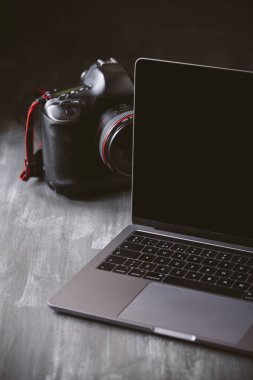 Laptop ve koyu ahşap arka plan üzerinde bir kamera.