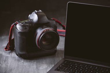 Laptop ve koyu ahşap arka plan üzerinde bir kamera.