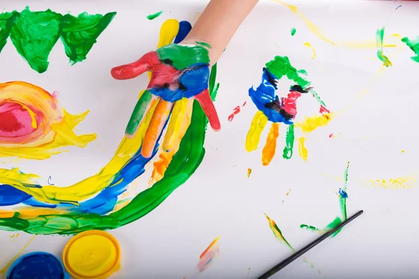 Маленькая рука ребенка научиться играть красочные цвета на белой бумаге — стоковое фото
