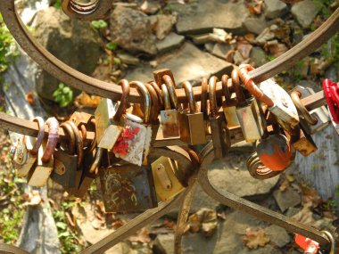 Köprüye bağlı çeşitli şekillerde asma kilitler, paslanmış kilitlerle süslenmiş köprü.