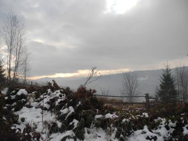 the sky is covered with clouds, fog in the mountains