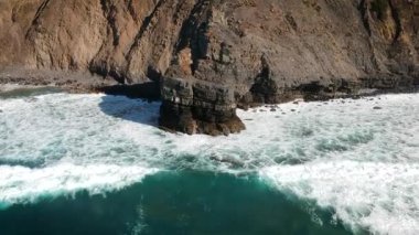 Portekiz, Algarve 'deki bir plajın kıyısındaki kayalıklara çarpan beyaz su dalgalarının görüntüsü yapıldı..