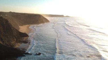 Güney Portekiz 'deki Algarve' de gün batımında kayalıklarla sahile vuran dalgaların hava aracı görüntüleri..