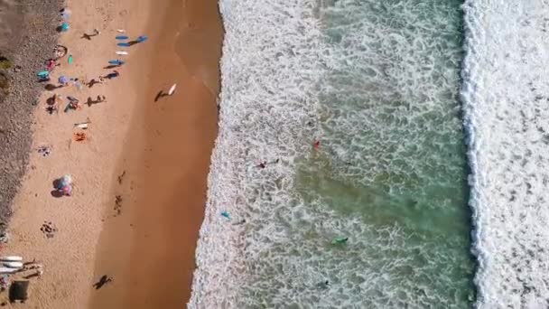 Un drone aérien d'une vague frappant une plage où les gens nagent et surfent en Algarve, Portugal .