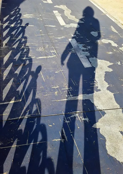A woman\'s shadow on a bike path.