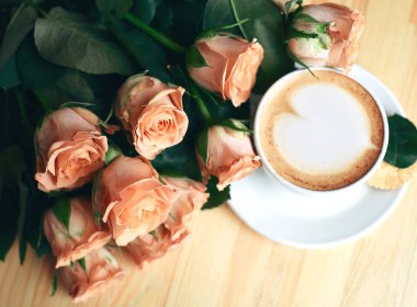 Kahvaltı için bir fincan kapuçino ve güller.