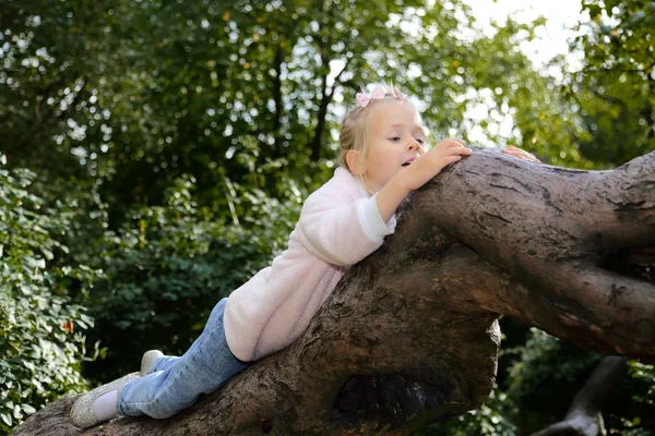 Little girl climbs a tree