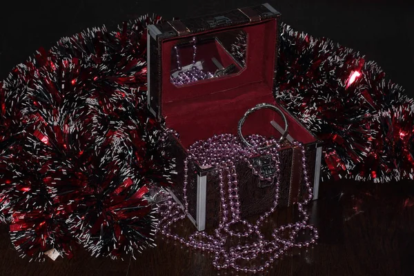 Casket with beads and jewels. Red velvet upholstery and mirror. Christmas red tinsel.