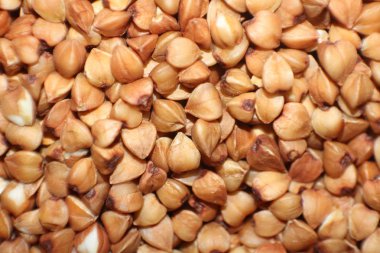 Ahşap mutfak masasına bir yığın karabuğday saçılmış. Sağlıklı bir yaşam tarzı için diyet ürünü. Fotoğrafta, kahverengi, bej ve pastel renkler..