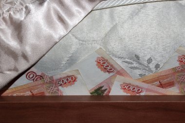 Para yatağın altında saklı. Faturaların köşeleri öne çıkıyor. Beş bin kırmızı beyaz banknotlu Rus rublesi..