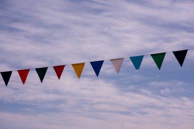 Açık mavi gökyüzüne asılı renkli sancaklar