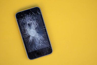 Cracked screen on mobile phone against colorful background