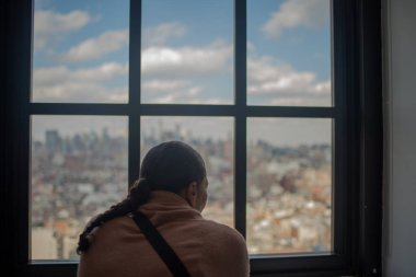Woman staring through window and looking at city view