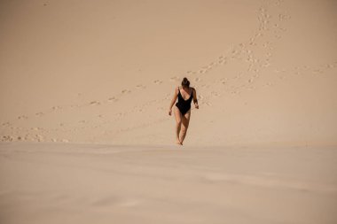 Kum tepesinde yürüyen bir kadın