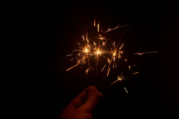 Dedos segurando fogos de artifício brilhantes acendeu no escuro — Fotografia de Stock