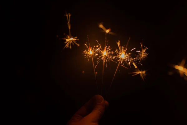 Mão segurando sparklers no escuro — Fotografia de Stock