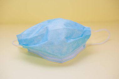 Sarı arka planda izole edilmiş cerrahi maske yakın çekim