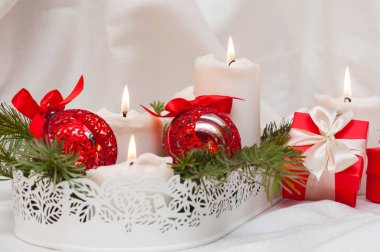 Noel ya da yeni yıl kartı. Arka planda yanan beyaz mumlar. Kırmızı toplar ve hediyeli kutular. Köknar dallarında dur