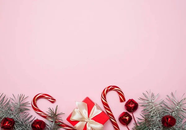 Composition de Noël. Cadeau de Noël, caramel, cônes de pin, sur fond rose. Pose plate, vue du dessus, espace de copie — Photo