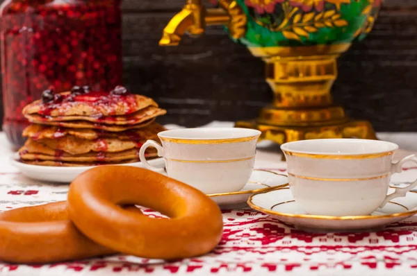 Karanlık bir arkaplanda yatay fotoğraf. Ön planda direksiyon simidi. Bakır semaver. Rus çay seremonisi. Masa örtüsünde iki fincan..