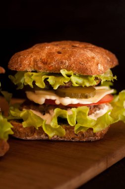Russian burgers on a wooden Board with tomatoes on a dark background