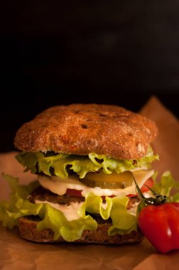 Russian burgers on tracing paper or food paper with tomatoes on a dark background