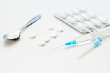 Beyaz arka planda tabletler. Beyaz pudralı kaşık. Sağlık için uyuşturucu ya da ilaçlar, hastane ya da klinik için pankart.