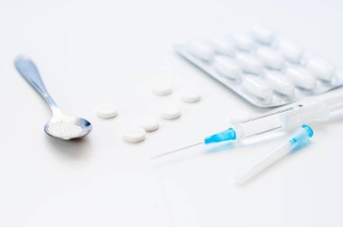 Beyaz arka planda tabletler. Beyaz pudralı kaşık. Sağlık için uyuşturucu ya da ilaçlar, hastane ya da klinik için pankart.