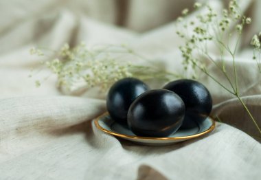 Tabakta siyah yumurta ve gri keten arka planda altın bir kenarı var. yatay resim