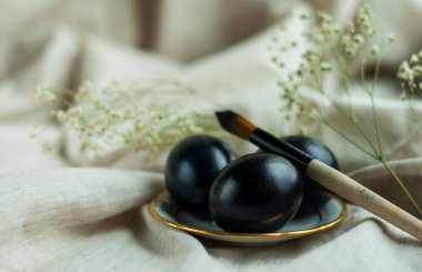 Altın kenarlı bir tabakta siyah yumurtalar ve gri keten arka planda bir fırça. yatay resim