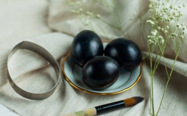 Altın kenarlı bir tabakta siyah yumurtalar ve gri keten arka planda bir fırça. yatay resim