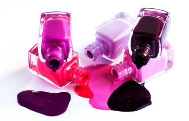 Masadaki bir şişeden dökülen pembenin çeşitli tonlarında oje.