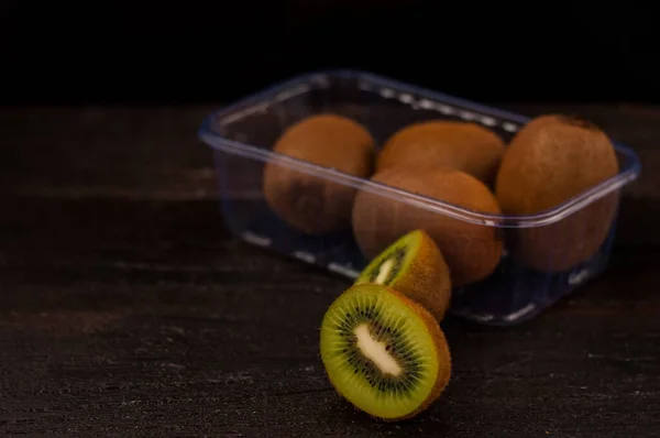 Green Cut Kiwi Lying Dark Table Plastic Box Whole Fruit — Stock Photo, Image