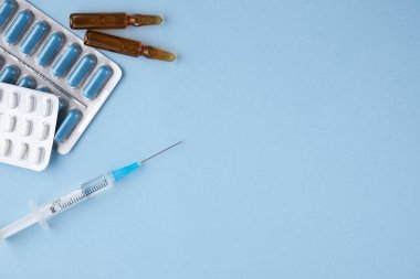 Tıbbi konu. Mavi arkaplandaki yazı için yeri olan pankart. Bir paket, ampul ve şırınga içinde mavi ve beyaz tabletler