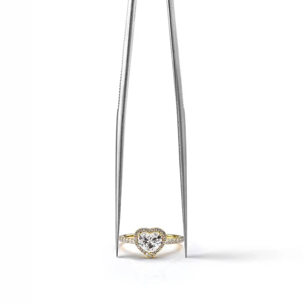Yellow Gold Heart Shaped Halo Engagement Ring Held in Tweezers Isolated on White Background