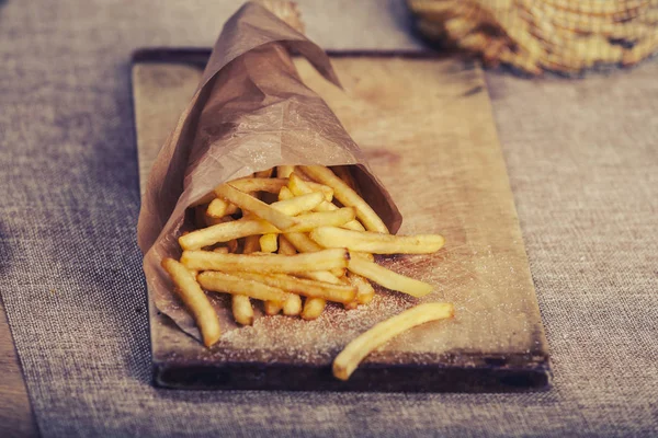 Tahta arka planda ketçaplı taze kızarmış patates kızartması.