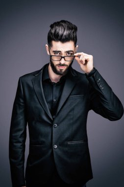 Portrait of a young businessman holding a pair of glasses, looking towards the lens