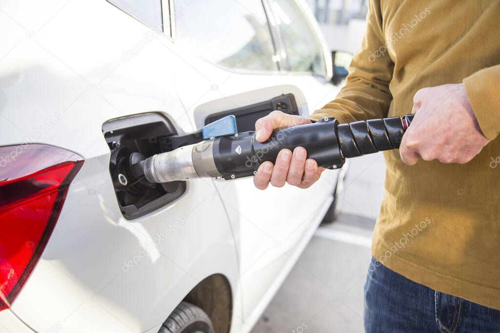 Man filling his car's tank with compressed natural gas, GNC. The vehicle has both a gas and a petrol tank. Concept Renewable Energies, ecological vehicle.