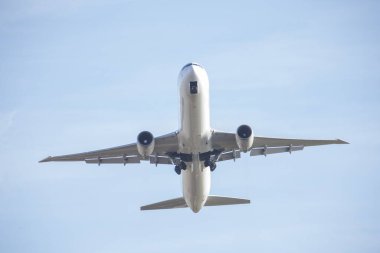 Aşağıdan uçan beyaz yolcu uçağı iniş takımlarını açıyor. Taşıma kavramı.