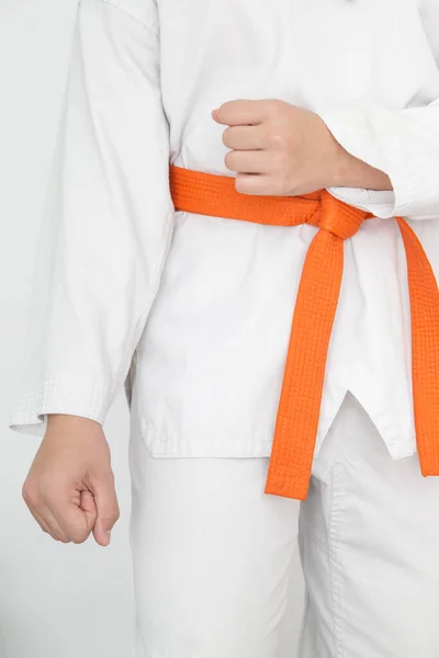 Photograph of girl in white kimono and orange belt in tae kwon do guard position. Photo in vertical. Martial arts concept.